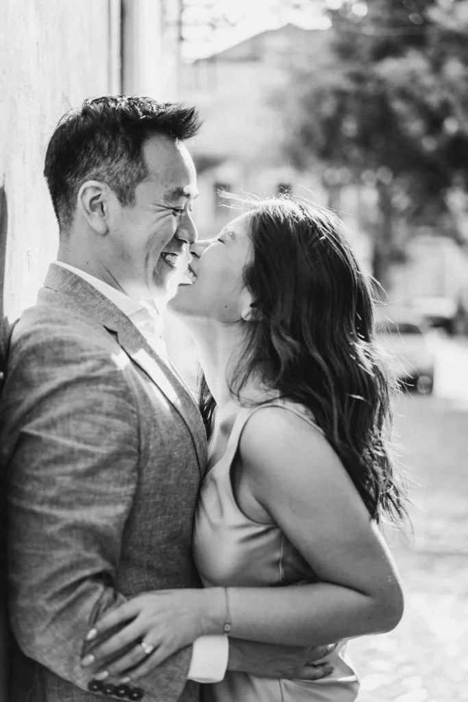 A black-and-white portrait of a couple laughing and leaning in close, radiating pure happiness.