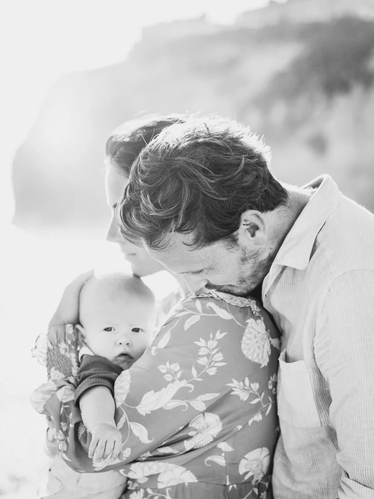 A black and white portrait of a father cradling his baby against his chest, capturing a tender moment.