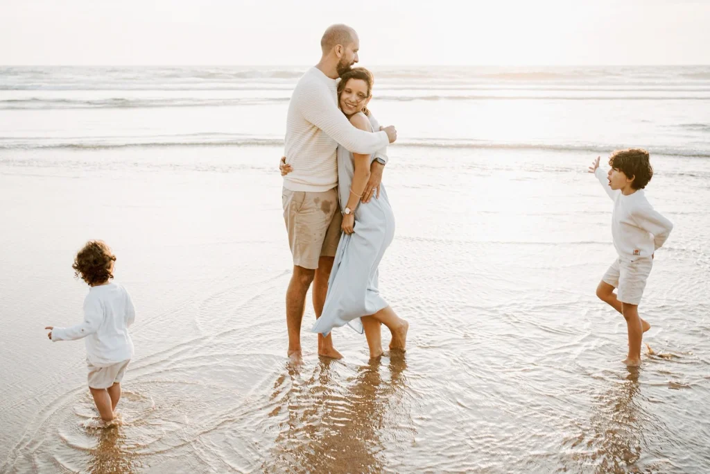 Couple embracing in the shallow waves of a beach at sunset, lost in a quiet moment together.