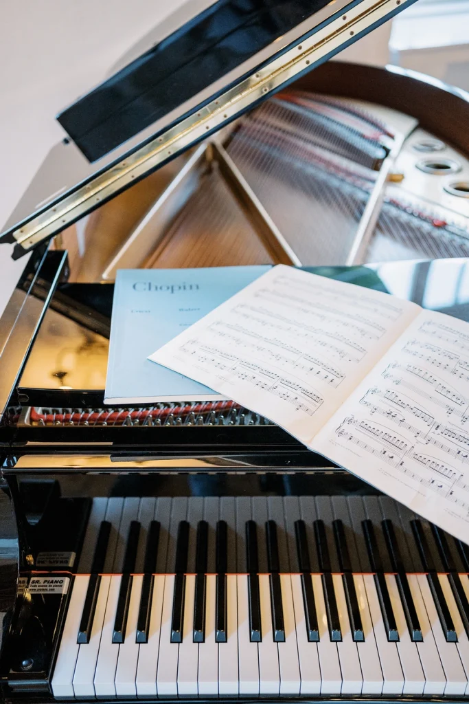 A grand piano with an open lid, featuring Chopin sheet music, set in an elegant wedding reception venue.