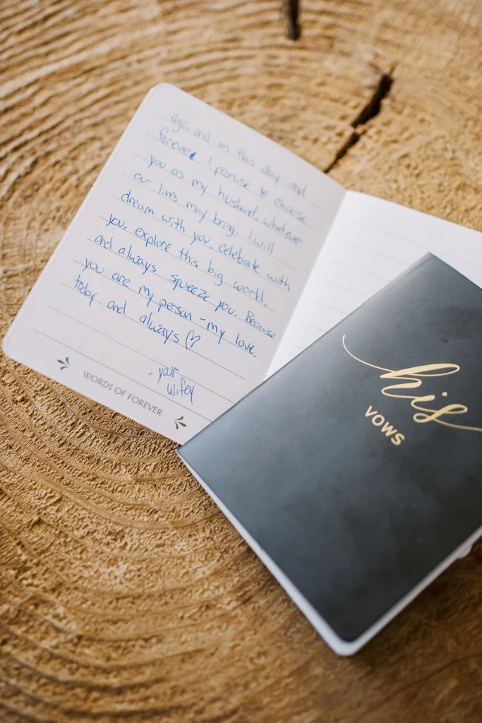 Close-up of handwritten wedding vows in a vow book placed on a wooden surface.