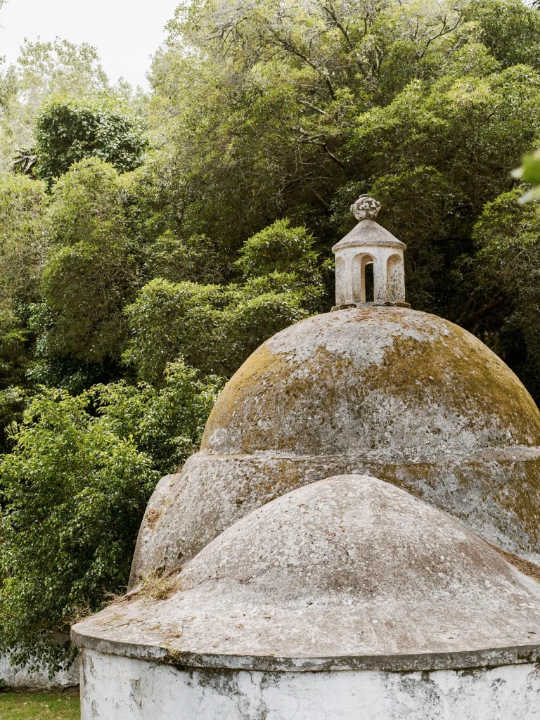 A weathered, historic dome structure surrounded by lush greenery in Portugal.
