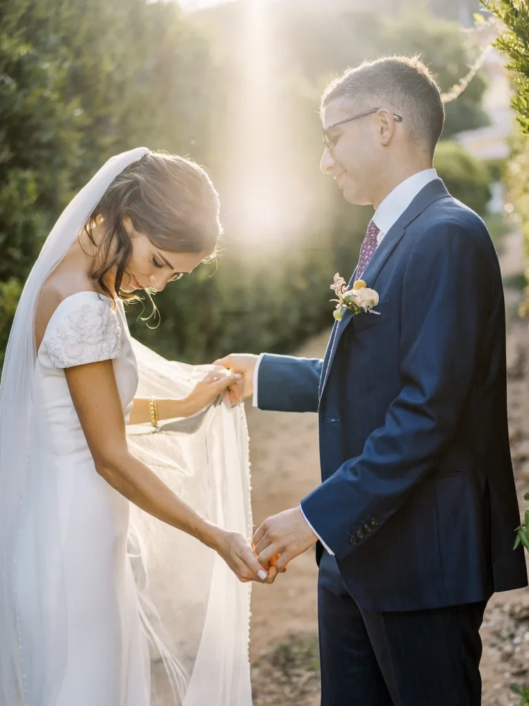 Bride smiling softly as she embraces the groom, with golden sunlight illuminating her face.