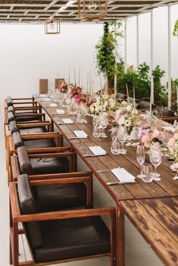 A beautifully decorated long wedding reception table with floral arrangements, candles, and elegant glassware.