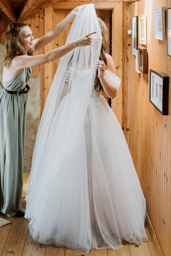 Bridesmaid helps bride adjust her veil before the ceremony.