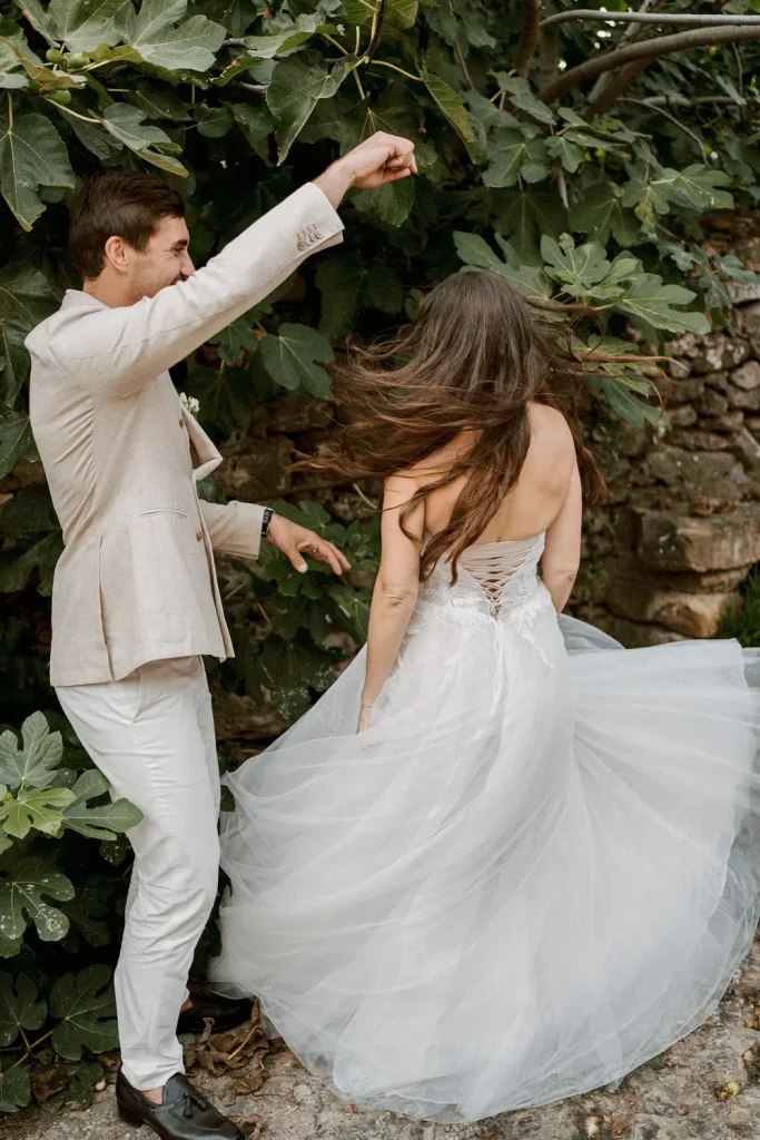 Groom playfully twirling the bride, her dress flowing beautifully as they dance outdoors.