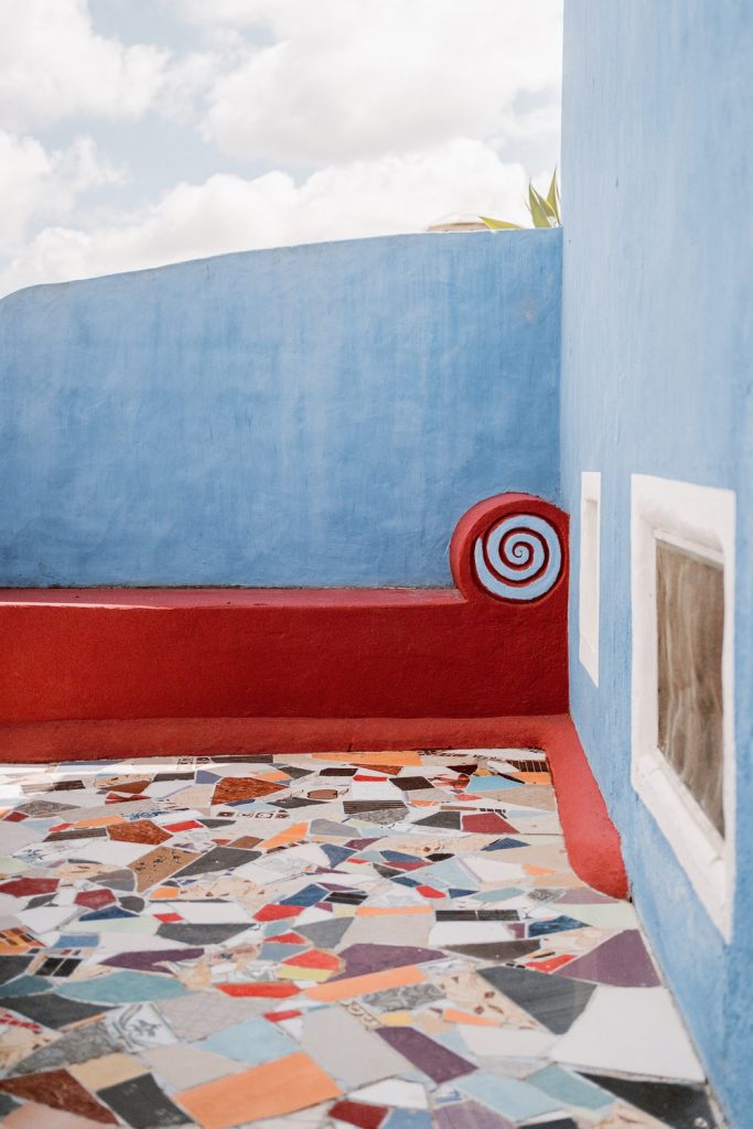 A vibrant blue and red mosaic wall at Paço Dilhas, with a spiral design and colorful tile flooring.